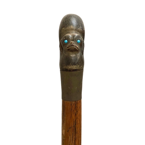 77 - A walking stick with horn handle carved with the mask of a Pekingese dog set with turquoise coloured... 