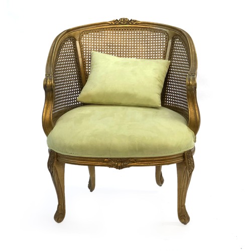 516 - A Louis XV style giltwood and caned bergere armchair, of recent manufacture, having a green suede up... 