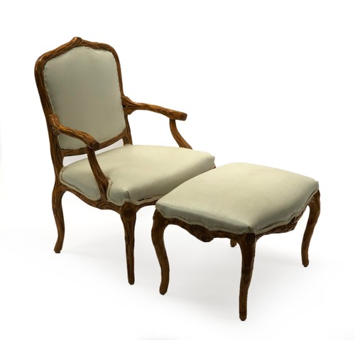 1642 - An Italian open arm chair, with matching footstool, the frames carved in naturalistic form, the chai... 