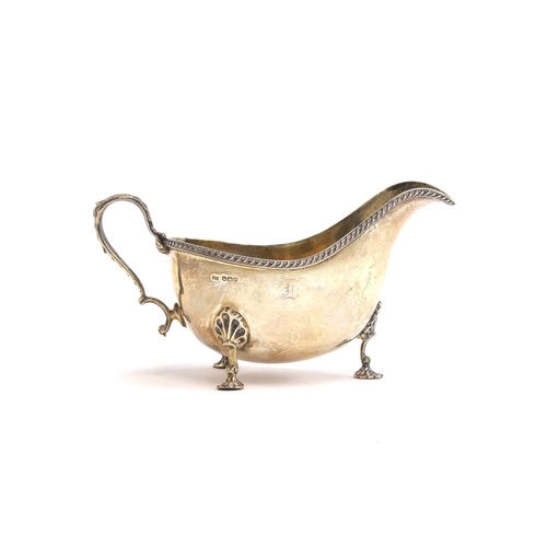 130 - A silver sauce boat by Walker & Hall, Sheffield 1948, silver gilt interior, gadrooned rim, on three ... 