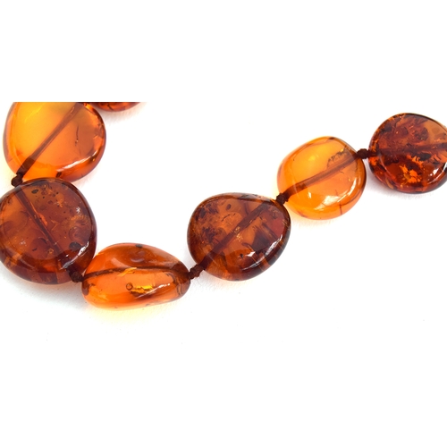 27 - An amber bead necklace, the beads graduating from 1.3cm to 2.3cm long, with a 9ct gold bolt ring cla... 