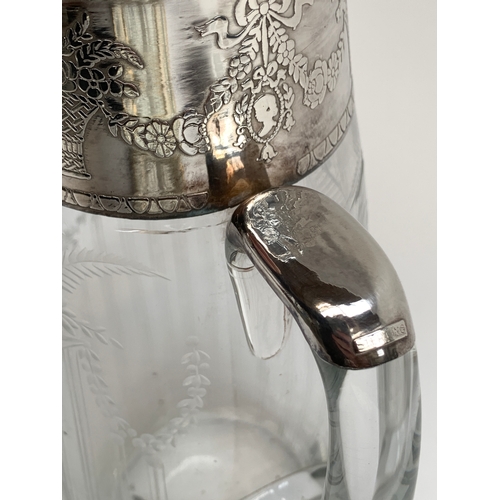 116 - A silver topped cut glass water jug (af), engraved with stands of flowers and floral swags, marked '... 