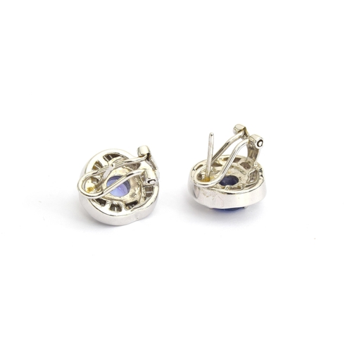 91 - A pair of heavy 18ct white gold earrings set with a central tanzanite, 6.5mm diameter, surrounded by... 