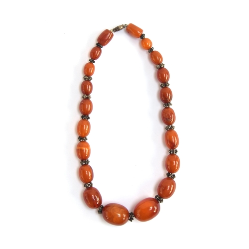 25 - An amber bead necklace with white metal granulated bead spacers, the amber beads graduating from 1.3... 