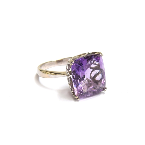 85 - A 14ct white gold and amethyst ring, the large amethyst mounted in a scrolling diamond studded pierc... 