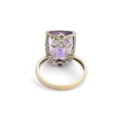 85 - A 14ct white gold and amethyst ring, the large amethyst mounted in a scrolling diamond studded pierc... 