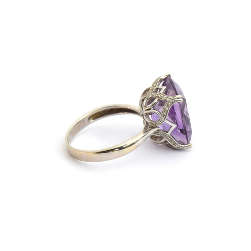 85 - A 14ct white gold and amethyst ring, the large amethyst mounted in a scrolling diamond studded pierc... 