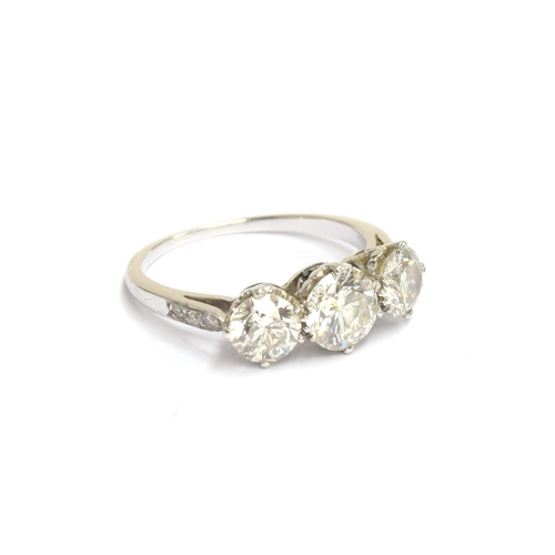 49 - An 18ct white gold diamond trilogy ring, the shoulders studded with diamonds, the three brilliant cu... 
