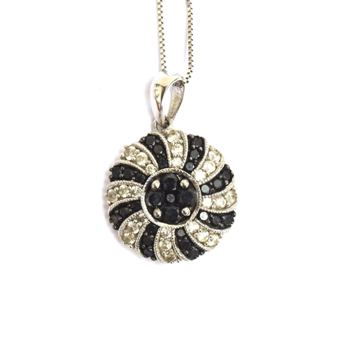 63 - A 14ct white gold pendant set with black and white diamonds in a swirl design, 15cm diameter, on a 1... 