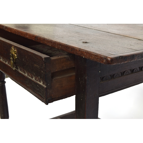 446 - A 17th century oak side table, plank top with cleated ends, single carved frieze drawer, on reel tur... 