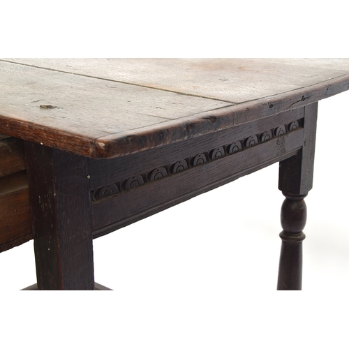 446 - A 17th century oak side table, plank top with cleated ends, single carved frieze drawer, on reel tur... 