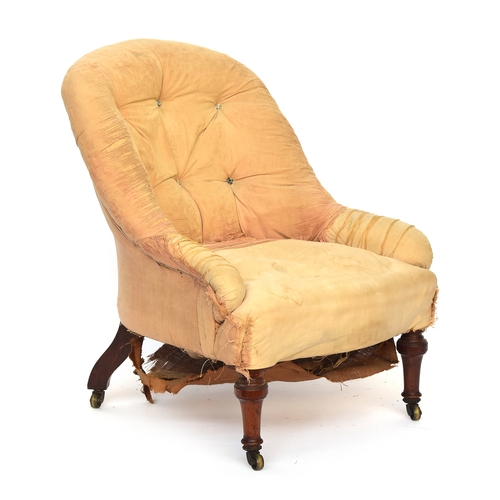 507 - A shapely Victorian button back armchair, in need of reupholstery, on turned front legs and brass ca... 