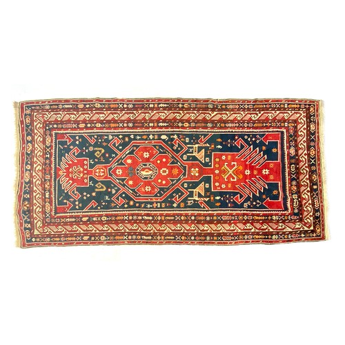 561 - A red ground tribal rug, 323x150cm