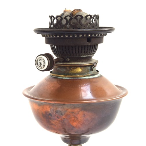 456 - Attributed to W.A.S. Benson, a brass and copper oil lamp, on four feet, with glass chimney, dimpled ... 