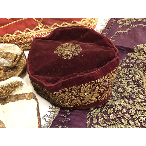 453 - An Indian metal thread embroidered purple silk panel; a red velvet and metal thread hat; tea cosy; a... 