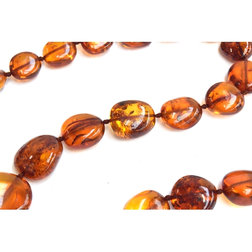 26 - An amber bead necklace, the beads graduating from 1.3cm to 2.3cm long, with a 9ct gold bolt ring cla... 