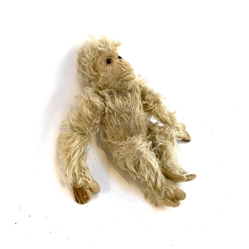 438 - An early 20th century monkey doll, straw filled body with articulated arms, 33cmL