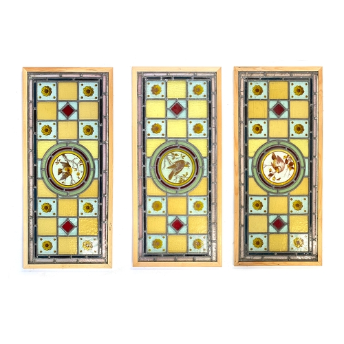 974 - Three Arts and Crafts stained glass panels, each with central roundel hand painted with a bird, 76.5... 