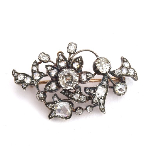 A 19th century diamond brooch, designed as a floral spray, with a variety of diamond cuts including old and rose cuts, set in silver with a gold backing and pin, the four largest diamonds totalling approx. 1.25cts (of which the largest central old cut diamond measures approx. 0.5cts), 3.9cm long, 5g