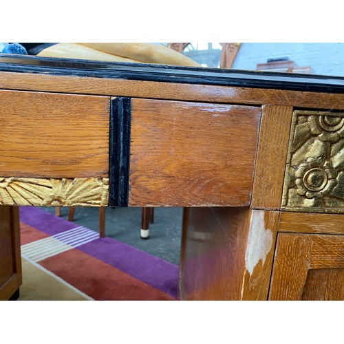 705 - A French Art Deco pedestal desk, parcel gilt and ebonised, with carved foliate and scallop panels, t... 