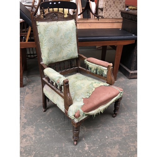 946 - A carved oak armchair, floral detail to pediment top, upholstered in a green fabric, spindle turned ... 