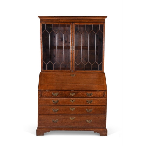 975 - A George III oak bureau bookcase, the fall enclosing a fitted interior, over four graduating drawers... 