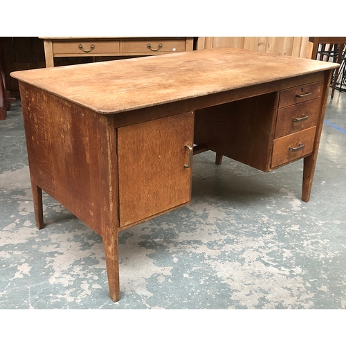 904 - A mid century oak desk, kneehole flanked by three drawers and a cupboard, 138x76x76cmH