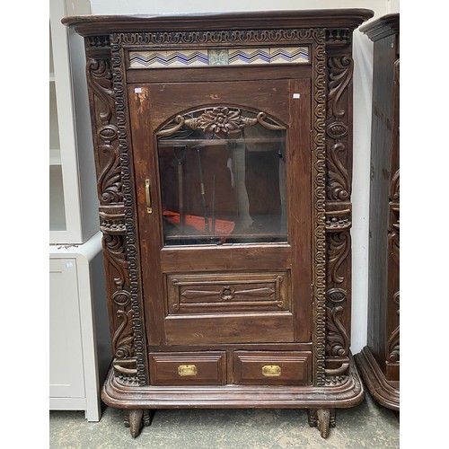 964 - An Indo-Portuguese carved cabinet with tiled frieze over a glazed cupboard door, two doors below, on... 