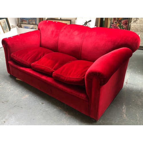 993 - A large red velvet upholstered country house sofa, three feather filled cushions, on compressed bun ... 