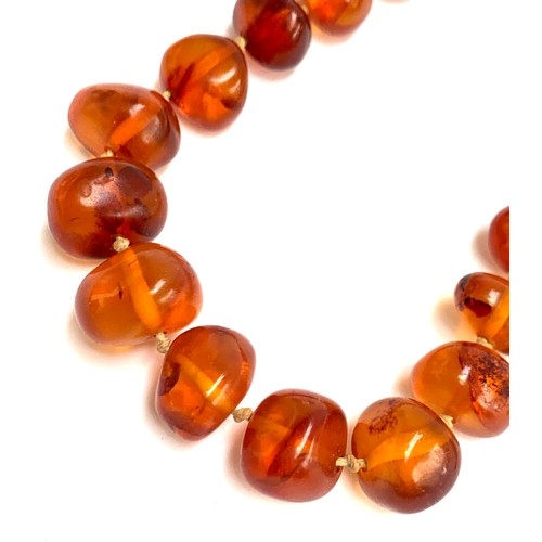 21 - An amber bead necklace, the beads graduating from 0.6cm to 1.5cm wide, 64cm long unclasped, knotted,... 