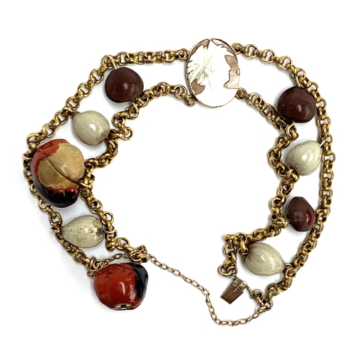 9 - An unusual yellow metal bracelet set with lucky Huayruro seeds and a small cameo, with a concealed s... 