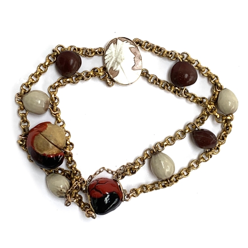 9 - An unusual yellow metal bracelet set with lucky Huayruro seeds and a small cameo, with a concealed s... 