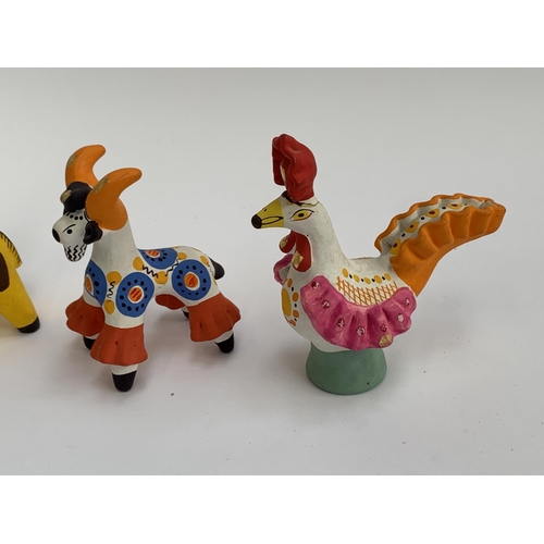 162 - Four Russian Dymkovo folk art pottery figurines, cockerel, bull, two bears, and a boy with an accord... 