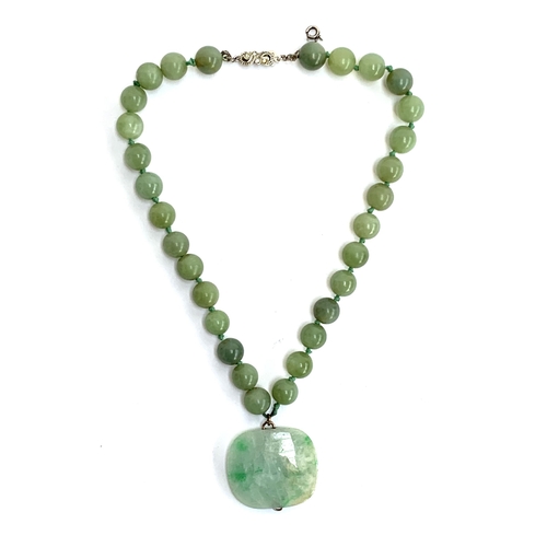 5 - A jade bead necklace, the 30 beads each approx. 1.1cm, suspending a large jade pendant with yellow m... 