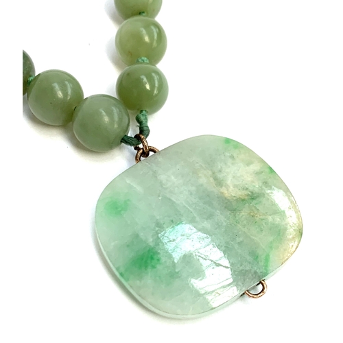 5 - A jade bead necklace, the 30 beads each approx. 1.1cm, suspending a large jade pendant with yellow m... 