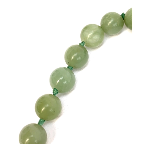 5 - A jade bead necklace, the 30 beads each approx. 1.1cm, suspending a large jade pendant with yellow m... 