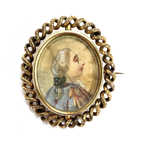 38 - A Victorian yellow metal brooch, the swivel locket containing a portrait miniature on silk on one si... 