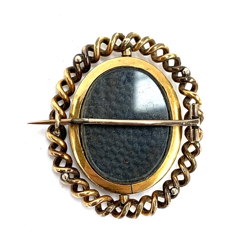 38 - A Victorian yellow metal brooch, the swivel locket containing a portrait miniature on silk on one si... 