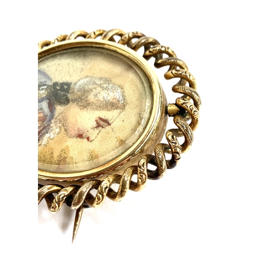 38 - A Victorian yellow metal brooch, the swivel locket containing a portrait miniature on silk on one si... 