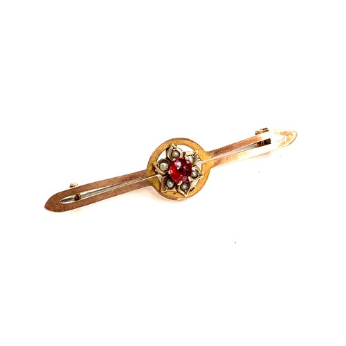 46 - An Edwardian gold floral bar brooch set, the flower with a central garnet surrounded by seed pearl p... 