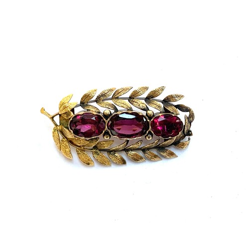 33 - A yellow metal brooch set with three almandine garnets within a laurel wreath (af), 4cmL, 5.2g gross... 