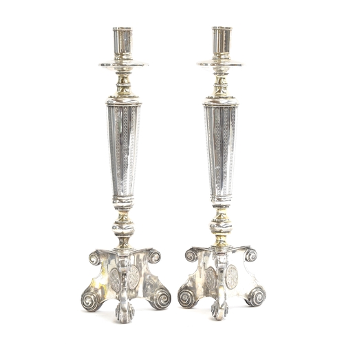 203 - A pair of continental silver plated candlestick on triform bases with floral roundels, in the manner... 