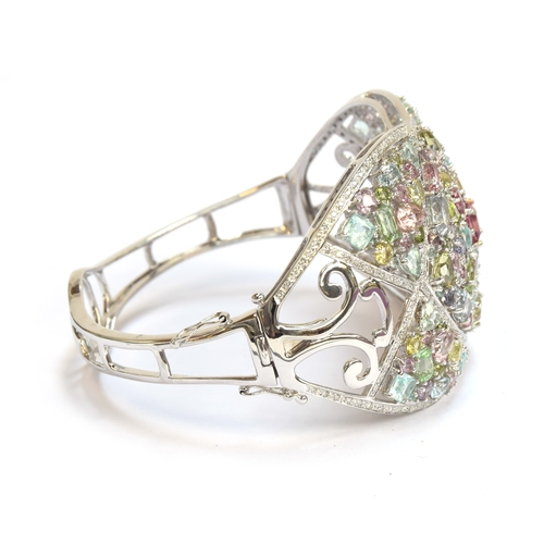 90 - A heavy 18ct white gold, tourmaline and diamond bangle, set with a total of 25.2cts of stones includ... 