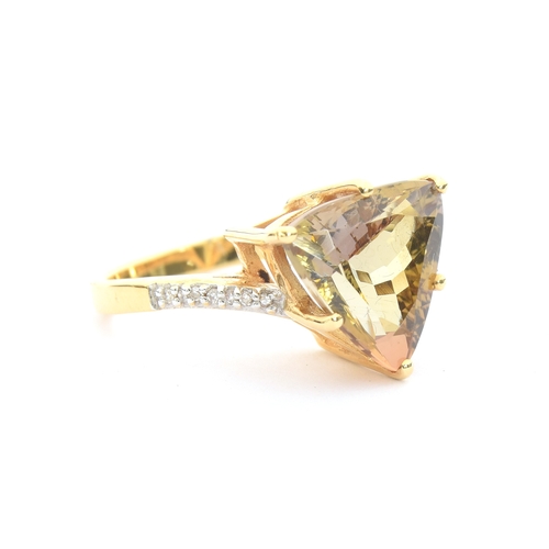 103 - An 18ct gold mounted yellow tanzanite and diamond ring, the trillion cut tanzanite weighing 7cts and... 