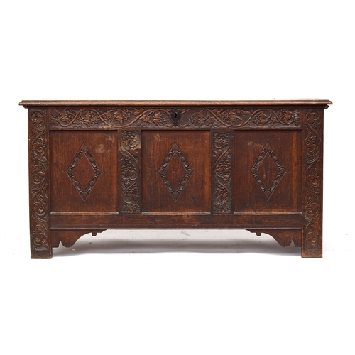 364 - An 18th century three panel oak coffer, with lozenge carving, the styles carved with stylised grape ... 