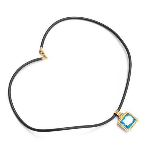 30 - A contemporary 18ct gold and blue topaz pendant on a black rubber cord with an 18ct gold clasp, the ... 