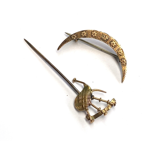 21 - A 9ct gold crescent moon brooch, 3.3cmW, gross weight 1.6g; together with a yellow metal bagpipe sti... 