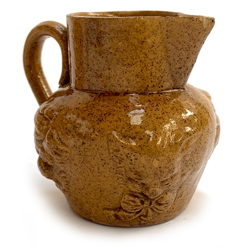 101 - An unusual small stoneware jug moulded with Louis Wain style cartoon cat and dog faces, 7cm high