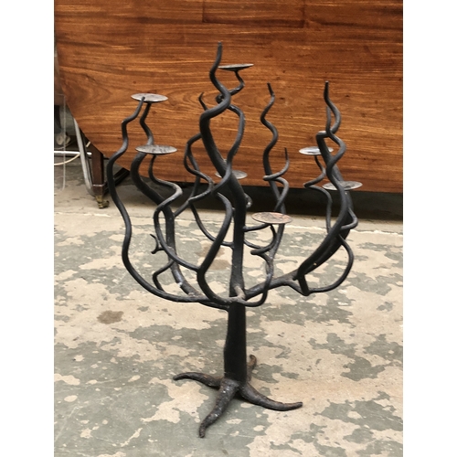 788 - A wrought iron floor standing candle holder with five sconces, 108cmH; together with a further wroug... 