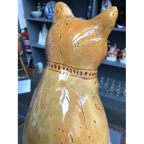 67 - A Welsh Claypits Ewenny pottery seated cat c.1900, in mustard glaze with incised detail, firing faul... 